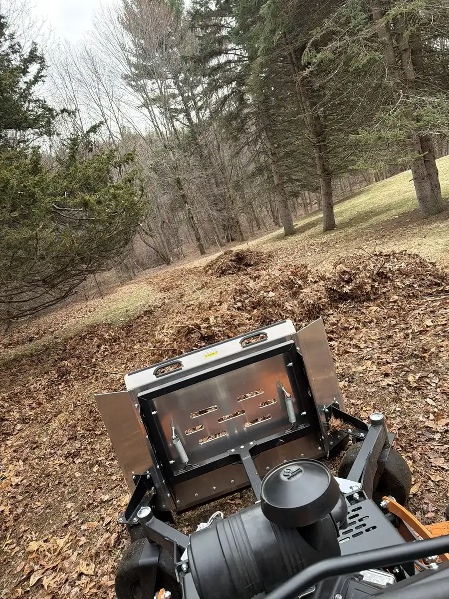 Stand-on mower with mulching deck grinding leaves during a fall cleanup in Southern New Hampshire