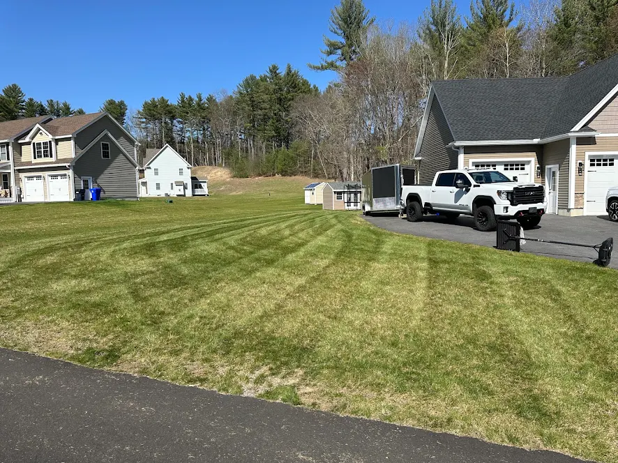 Freshly striped Hudson NH lawn with the Craig Property Maintenance truck and trailer on site