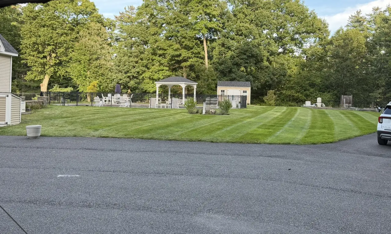 Striped backyard lawn with gazebo and fence line in Southern New Hampshire