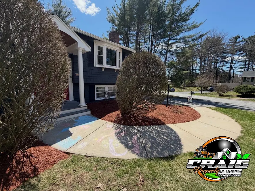 Fresh red mulch beds and curved concrete walkway on a Hudson NH front yard