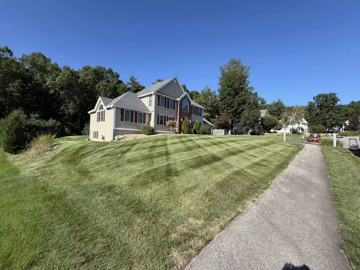 Striped sloped front lawn along a driveway in Southern New Hampshire