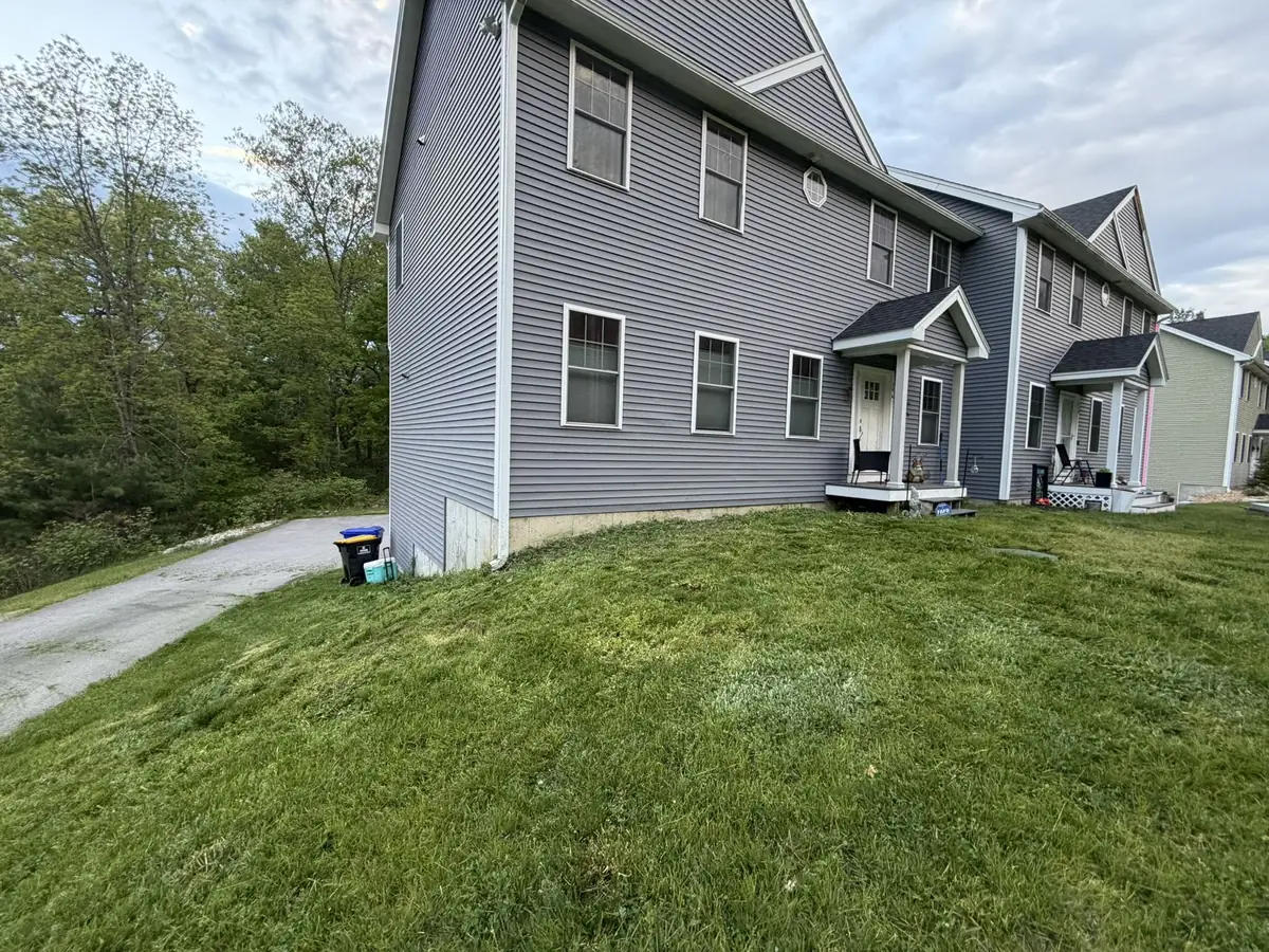 Bare foundation strip along a gray colonial before a crushed stone bed installation